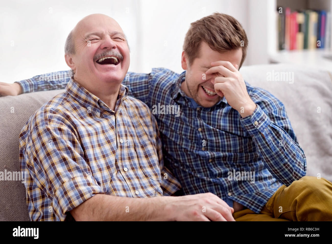 Deux hommes, le père et le fils sont assis sur le canapé dans le salon à la maison et n'oubliez pas le plus drôle des événements du passé. Ils se moquent de la plaisanterie. Bonne fa Banque D'Images