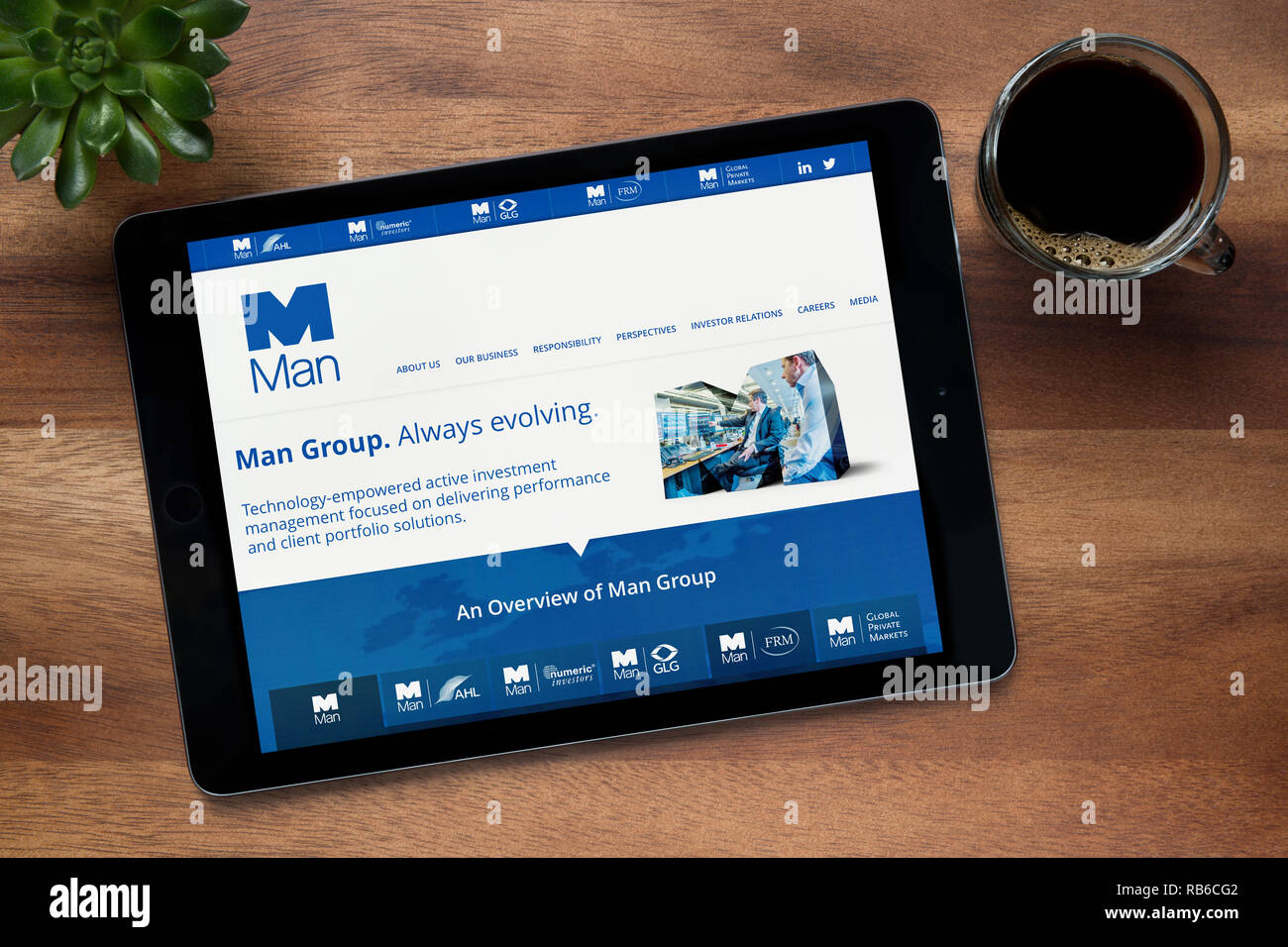Le site internet de Man Group est considéré sur une tablette iPad, sur une table en bois avec une machine à expresso et d'une plante (usage éditorial uniquement). Banque D'Images