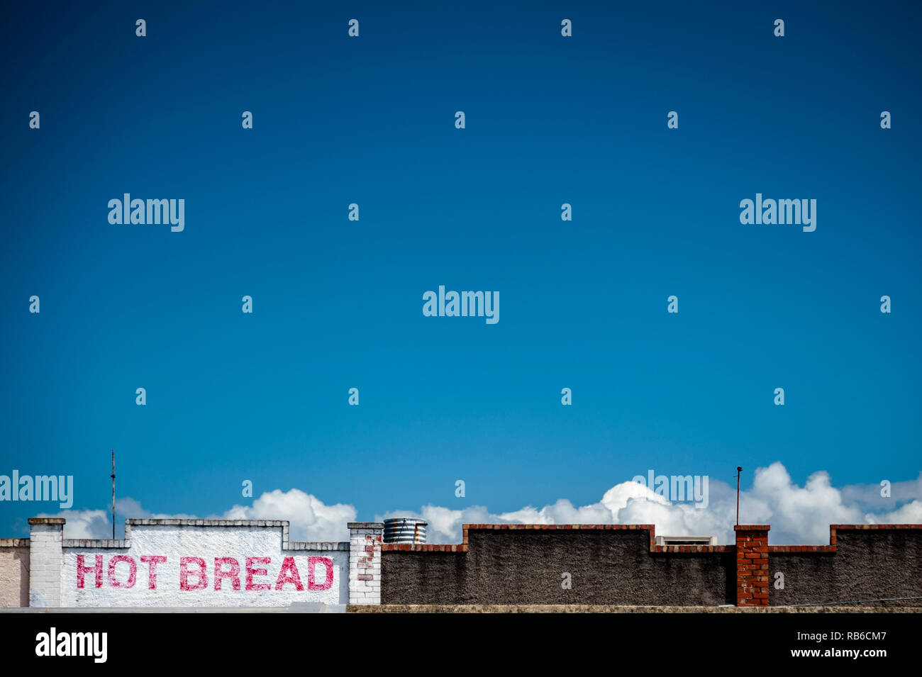 Un vieux pain chaud peintes sur le dessus d'un bâtiment avec un grand ciel bleu et nuages à l'horizon Banque D'Images