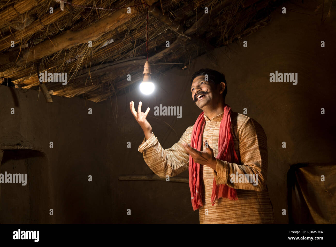 L'homme de l'Inde rurale enchanté à la lueur de l'ampoule électrique et de l'électricité d'atteindre son domicile après une longue attente Banque D'Images