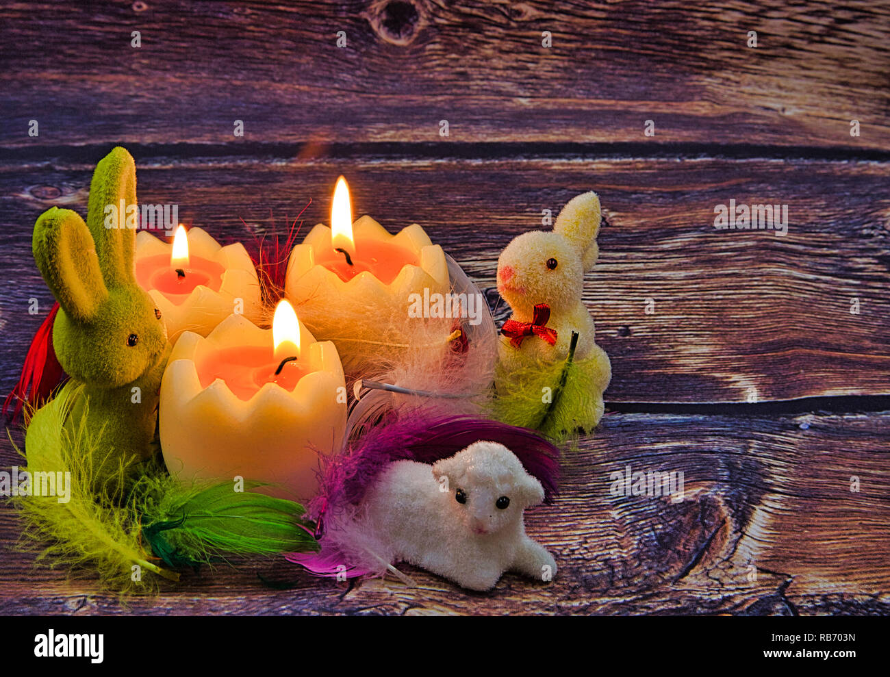 Composition Pâques romantique avec des bougies allumées, des lapins de Pâques et d'agneau dans les plumes colorées dans un style vintage Banque D'Images