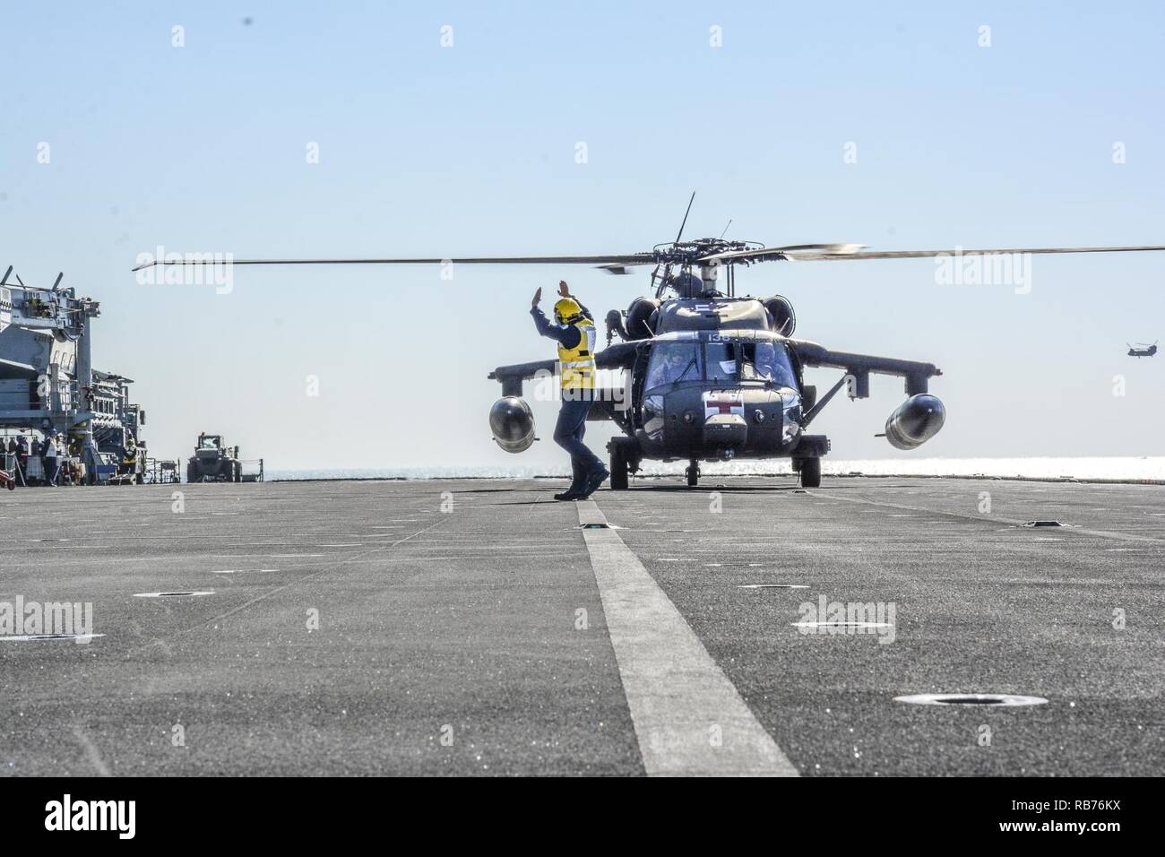 Les pilotes d'un UH-60 Black Hawk de la Compagnie Charlie, 1er Bataillon, 111e Régiment d'aviation, prendre leurs directives d'atterrissage de la Leading Aircraftman avec la Royal Navy le HMS Ocean, au cours de la qualification d'appontage d'une mission de formation commune dans le Golfe Arabe, le 11 décembre 2016. Banque D'Images