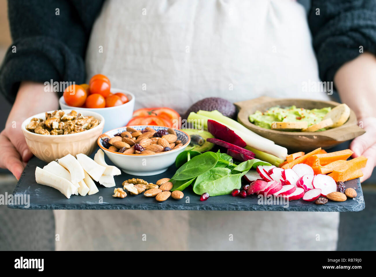 Woman holding repas sain, sélection de nettoyer les aliments biologiques : les légumes, les noix, l'avocat, les amandes, feuilles vertes Banque D'Images