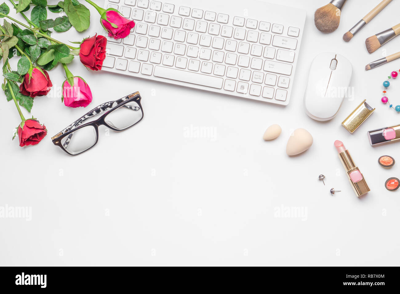 Bureau bureau avec clavier sans fil et des protocoles d', rose et rouge bouquet de roses, des cosmétiques sur fond blanc. Mise à plat. Vue d'en haut. Valentine se passe Banque D'Images