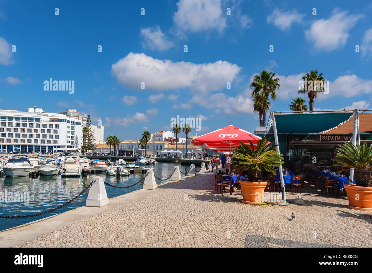 Les touristes à pied le long de la promenade du cours des bateaux à moteur en marina. Faro, Portugal Banque D'Images