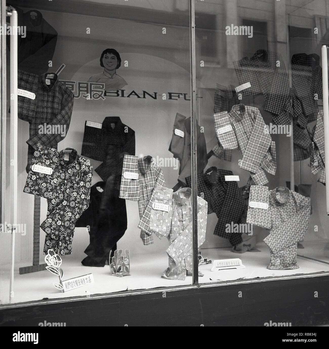 Années 1950, à l'histoire, Beijing, Chine. Magasin de vêtements pour hommes, une fenêtre de l'affichage de style chinois à motifs différents mens lâche ou chemises sport. Banque D'Images