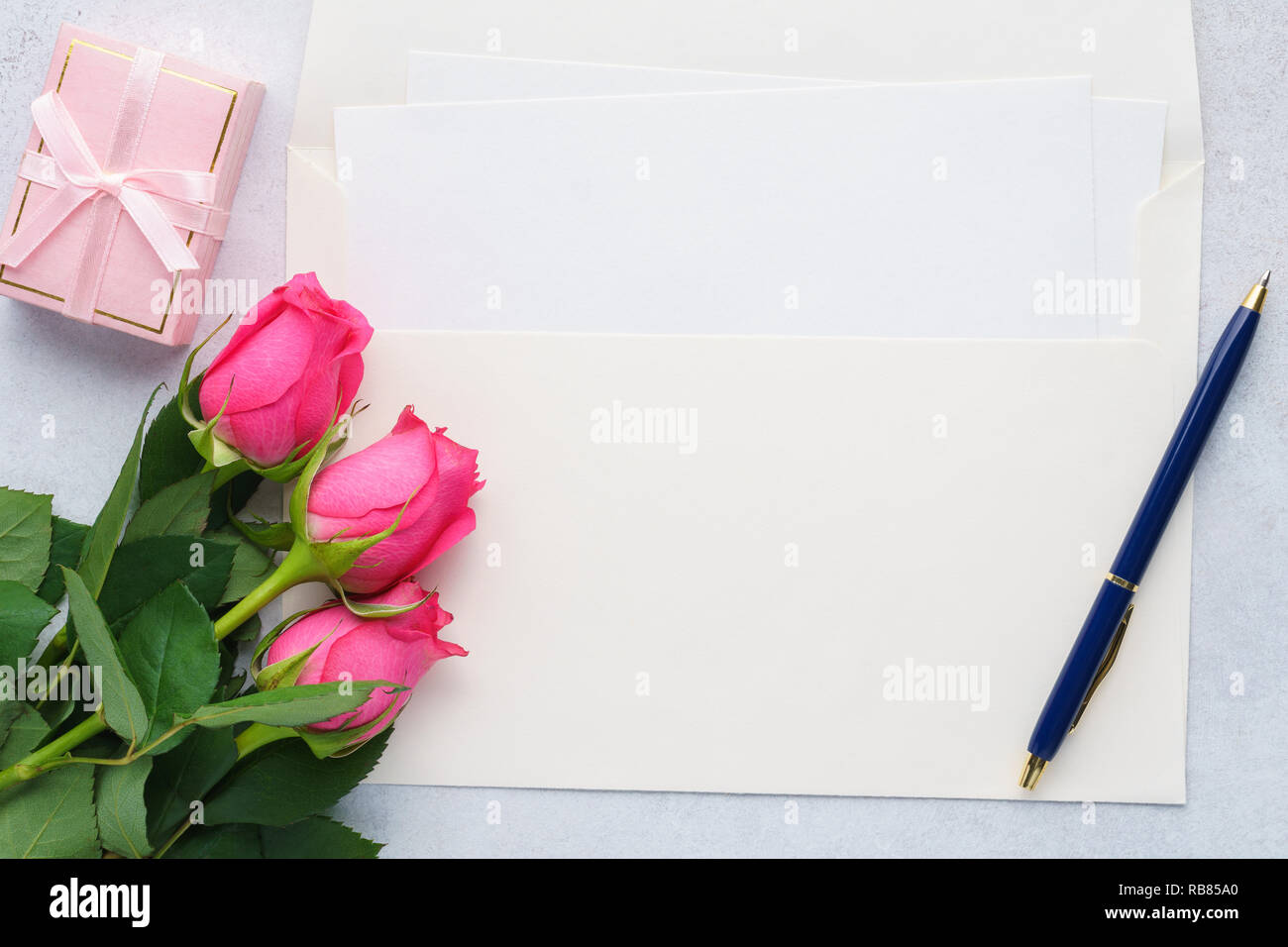 Lettre d'amour ou la Saint-Valentin une maquette de carte de vœux. Liste vide de papier, enveloppe, roses rose, boîte cadeau et un stylo. Banque D'Images