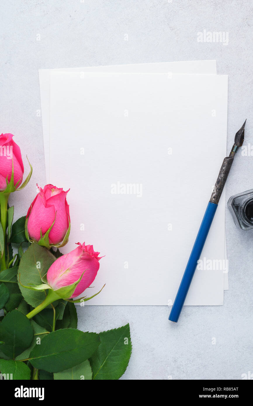 Liste vide de papier, rose roses, plume et encre. lettre d'amour pour la Saint-Valentin. Vue d'en haut. Banque D'Images