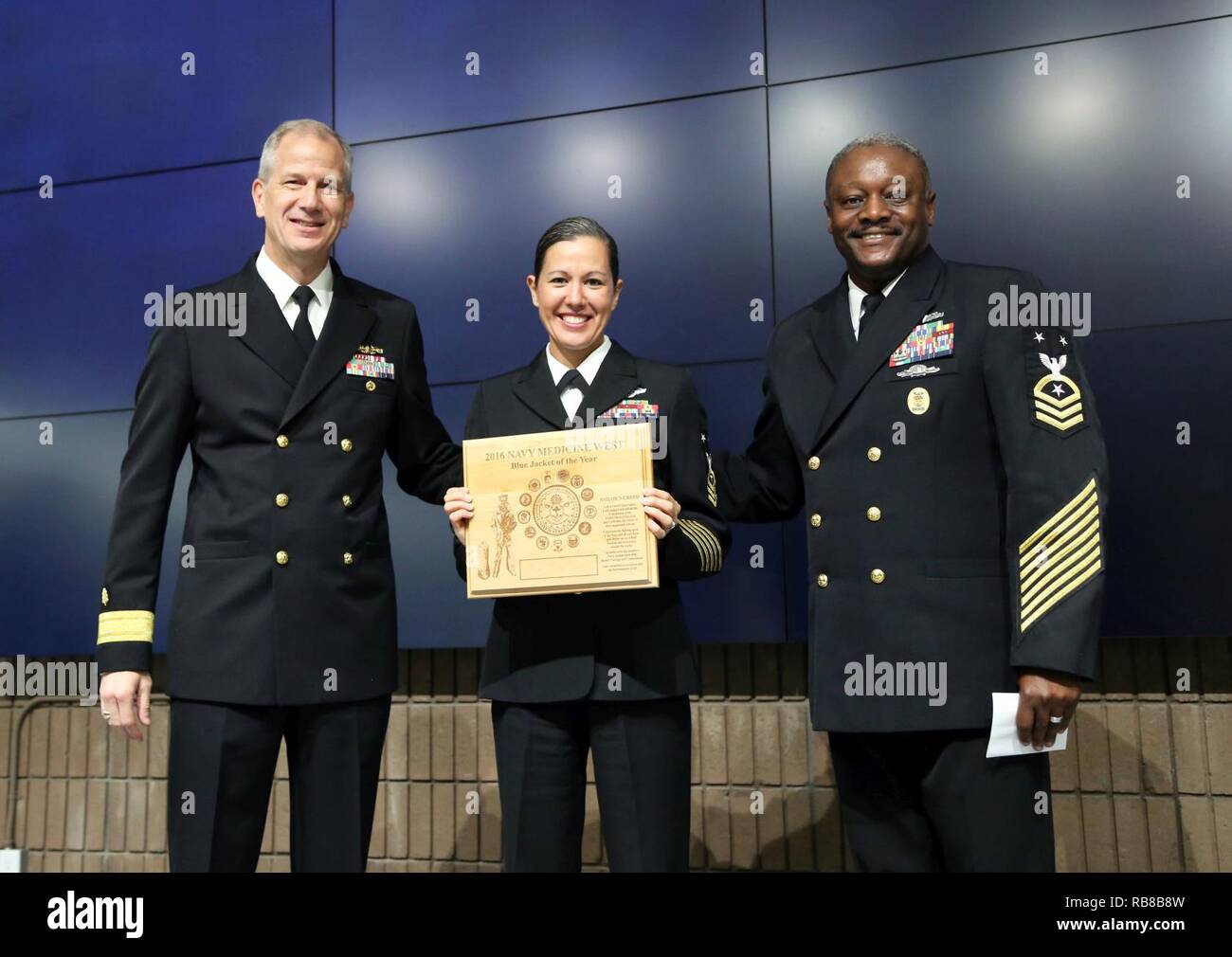 SAN DIEGO (Dec 9, 2016) Maître Premier maître de Ana Wood, chef principal de commande pour 1e Bn dentaire., Centre Dentaire Naval Camp Pendleton (au centre), reçoit une plaque pour la Marine veste bleue de l'ouest de la médecine de l'année au nom de Seaman Katie Yost, de la Naval Dental Center Camp Pendleton, dans un auditorium rempli de marins et civils de la Marine au siège de l'ouest de la médecine. Adm arrière. Paul Pearigen, commandant de la médecine de la Marine à l'Ouest (à gauche) et Master Chief Petty Officer Osée Smith, chef principal de commande, la médecine de la Marine à l'Ouest (à droite), a présenté la plaque. Banque D'Images