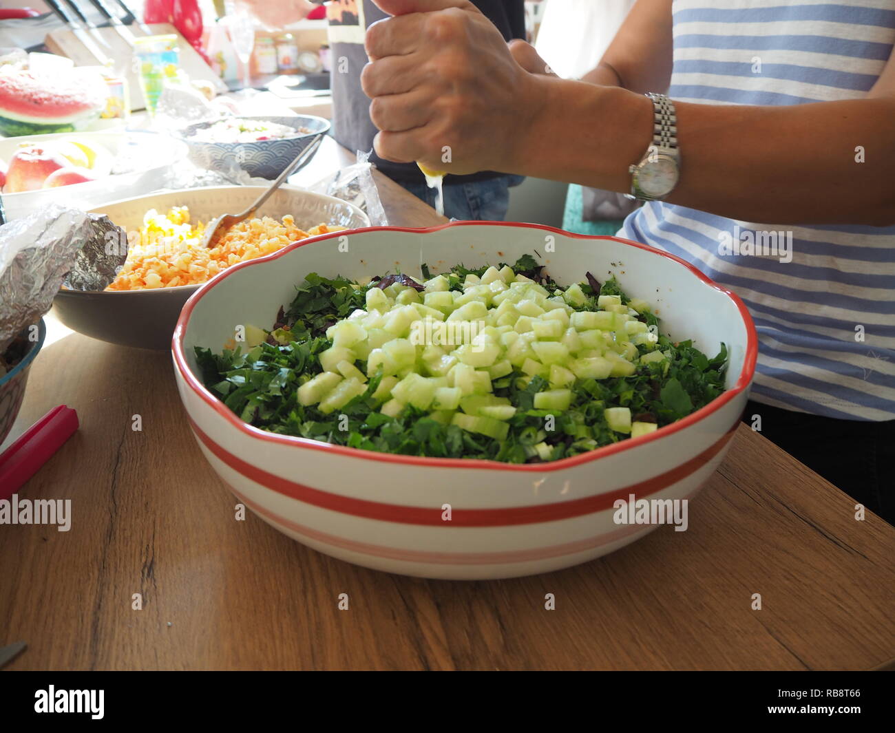 Femme préparant la salade et presser un citron dans la salade. Banque D'Images