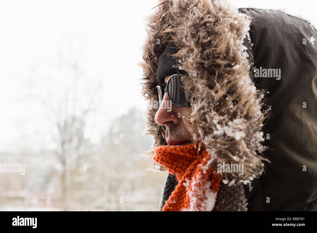 Portrait d'un homme portant un aventurier hiver chaud manteau vert avec la  fourrure capot, une casquette bleu, un foulard orange et noir lunettes  style rétro Photo Stock - Alamy