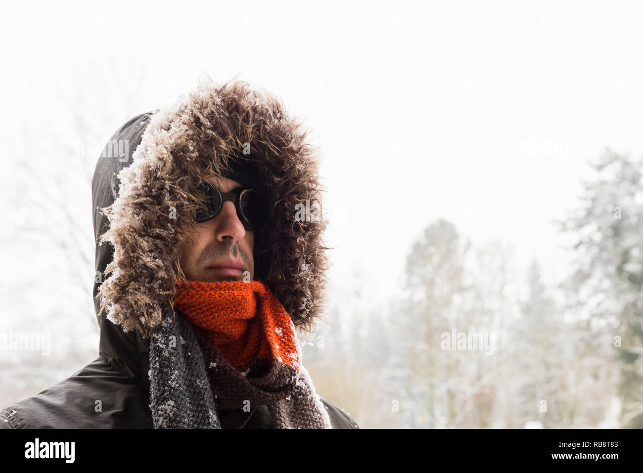 Portrait d'un homme portant un aventurier hiver chaud manteau vert avec la  fourrure capot, une casquette bleu, un foulard orange et noir lunettes  style rétro Photo Stock - Alamy