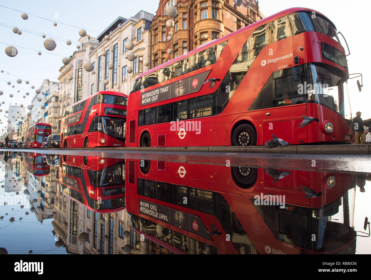 Les bus rouges se reflètent dans l'eau debout sur Oxford Street, Londres, à la suite d'une rafale d'eau principale dans l'un des plus achalandés du capital des rues commerçantes. Banque D'Images