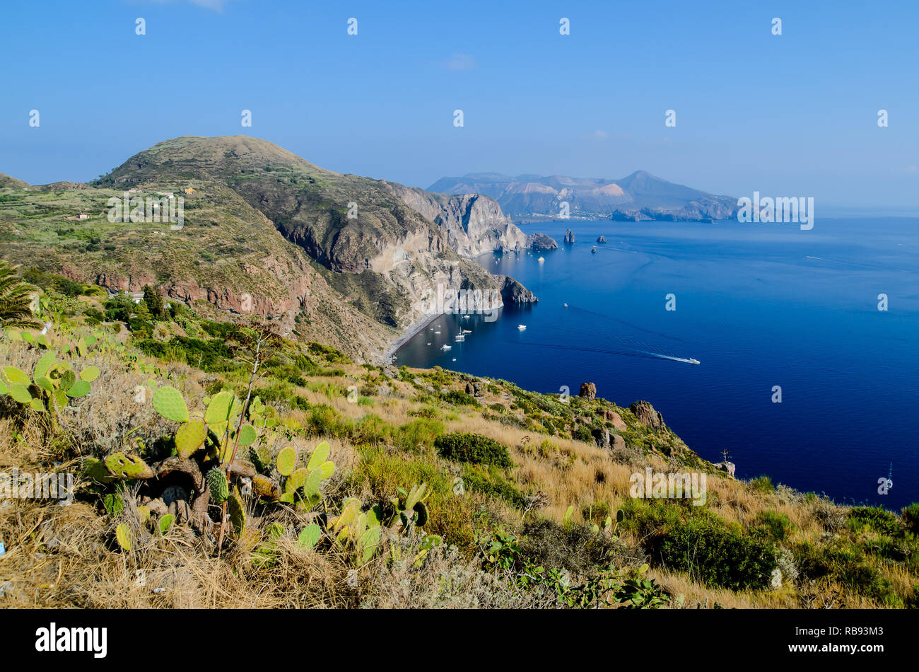 Vue imprenable sur la Valle Muria beach à Lipari et les faraglioni. Dans l'arrière-plan le cratère de l'île de Vulcano. Iles Eoliennes, Sicile Banque D'Images