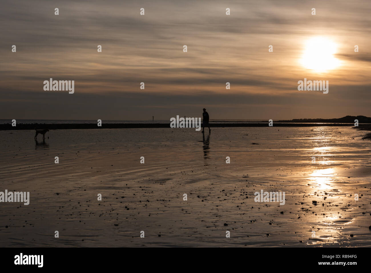 Coucher du soleil la création de silhouettes sur la plage Banque D'Images