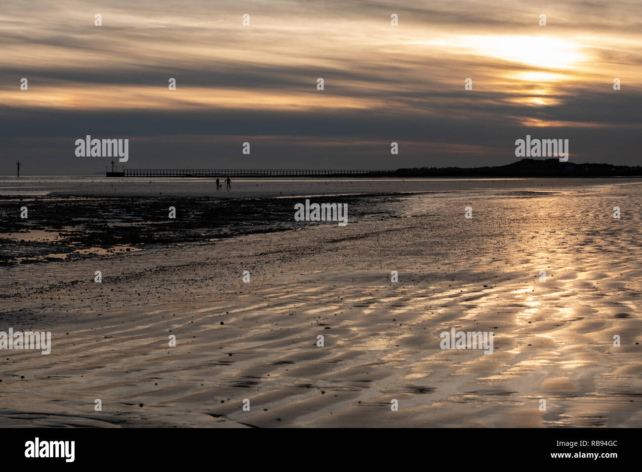 Coucher du soleil la création de silhouettes sur la plage Banque D'Images