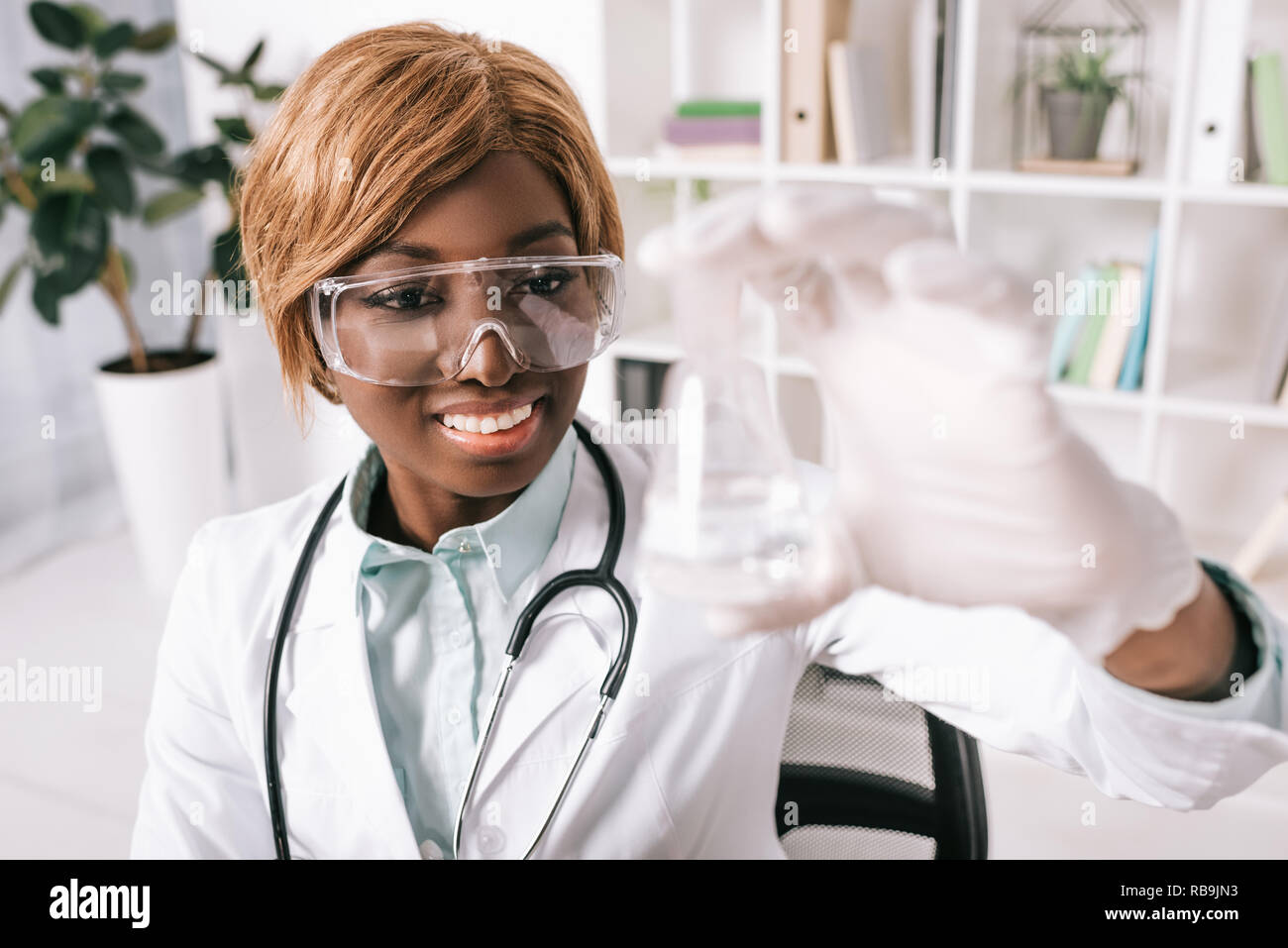 Belle african american scientist looking at test tube de liquide Banque D'Images