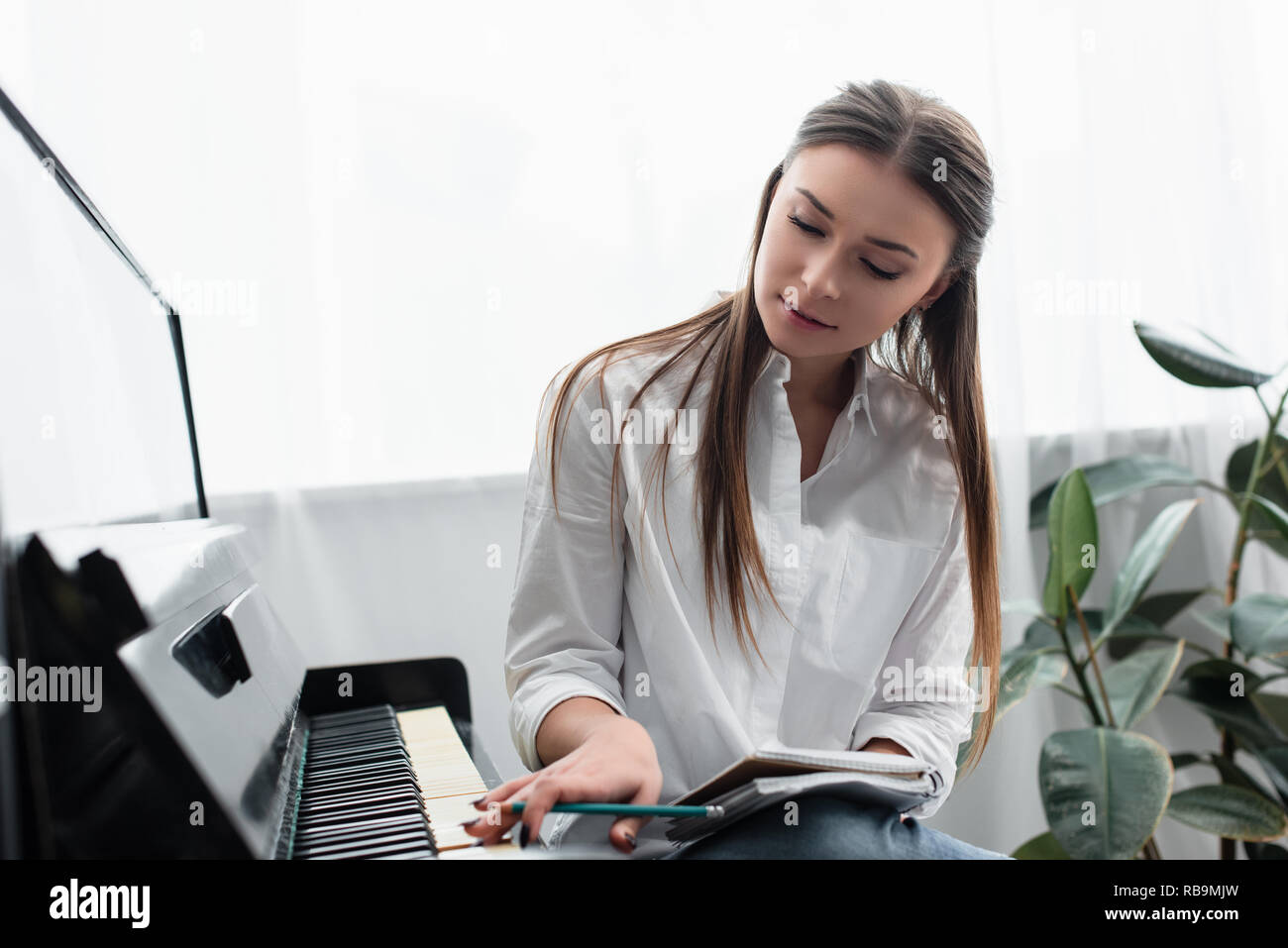 Belle fille avec un ordinateur portable à jouer du piano et composer de la musique à la maison Banque D'Images