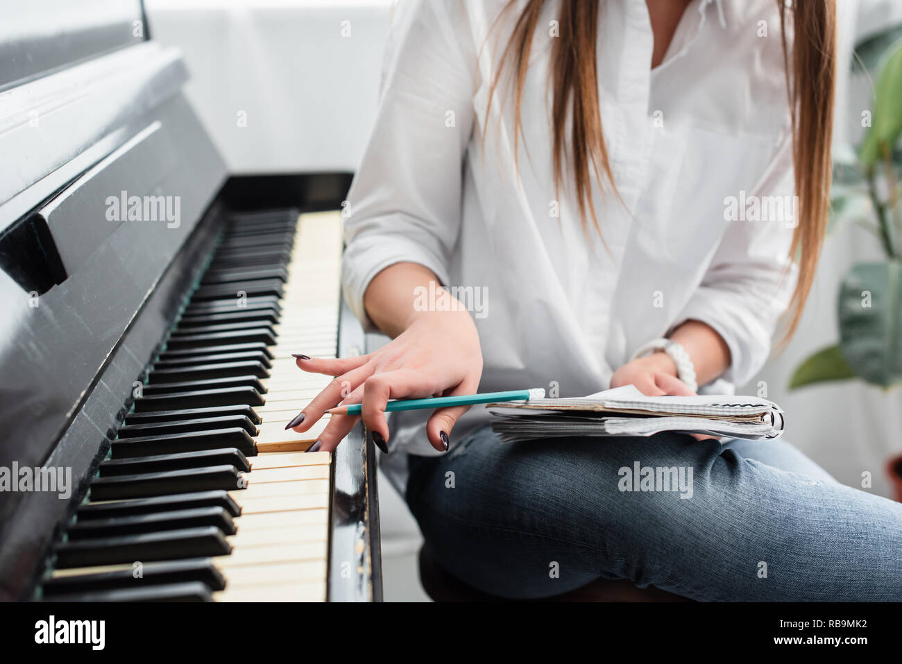 Portrait de jeune fille en chemise blanche avec un ordinateur portable à jouer du piano et composer de la musique à la maison Banque D'Images