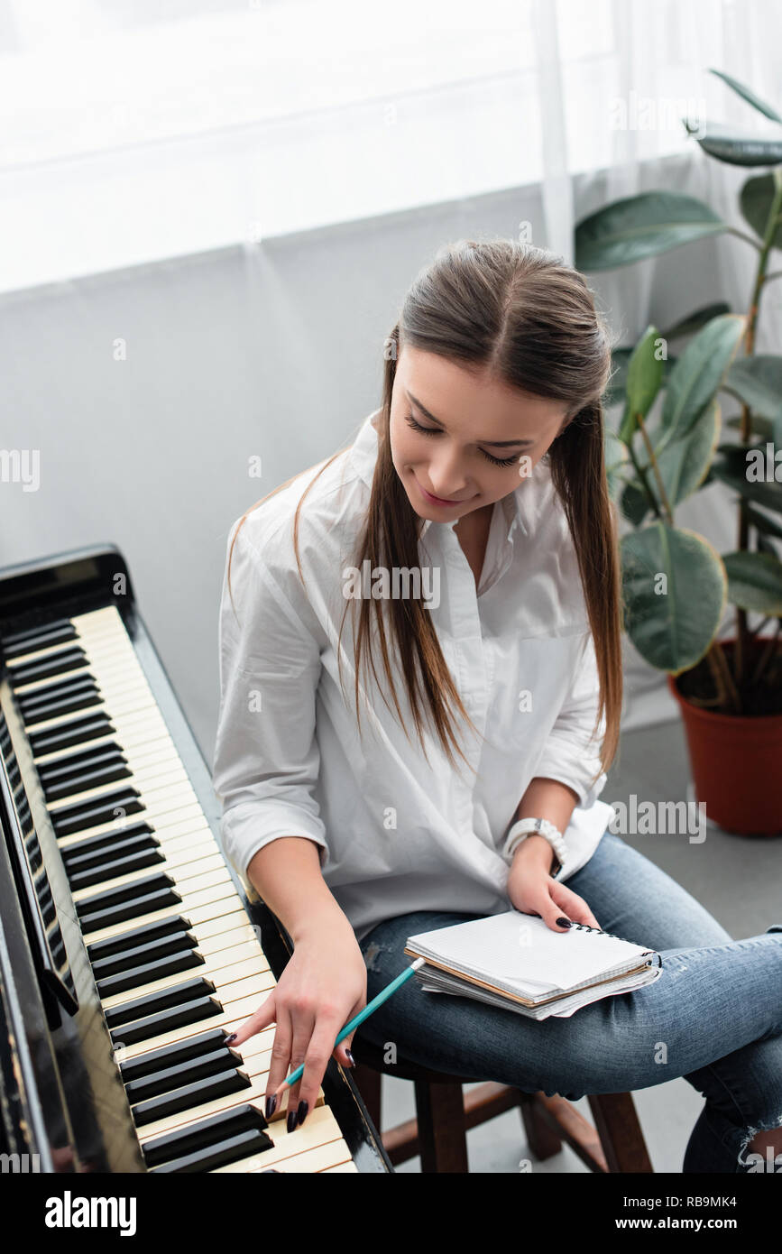 Jolie jeune fille avec un ordinateur portable à jouer du piano et composer de la musique à la maison Banque D'Images