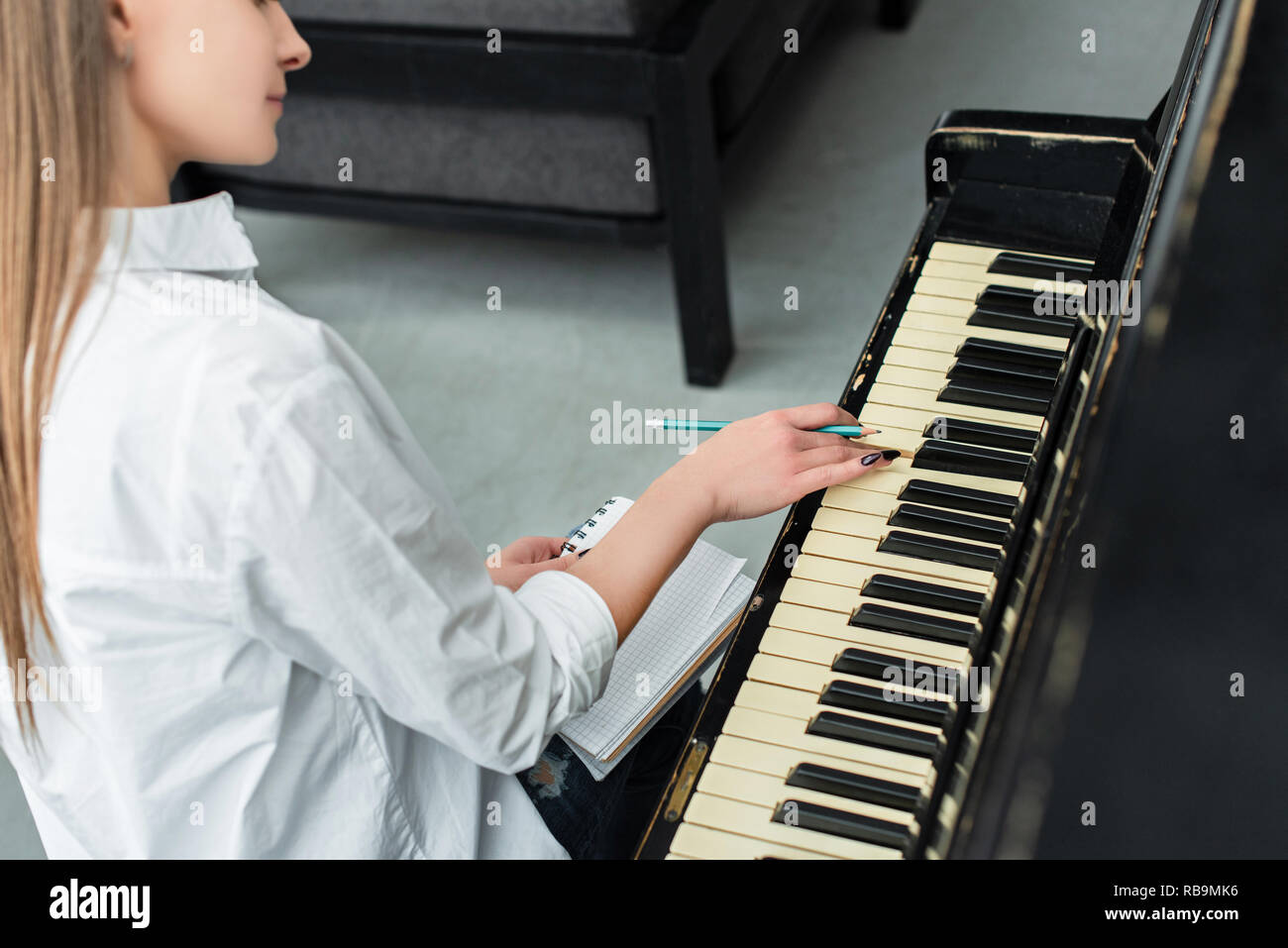 Vue partielle de la fille avec un ordinateur portable à jouer du piano et composer de la musique à la maison Banque D'Images