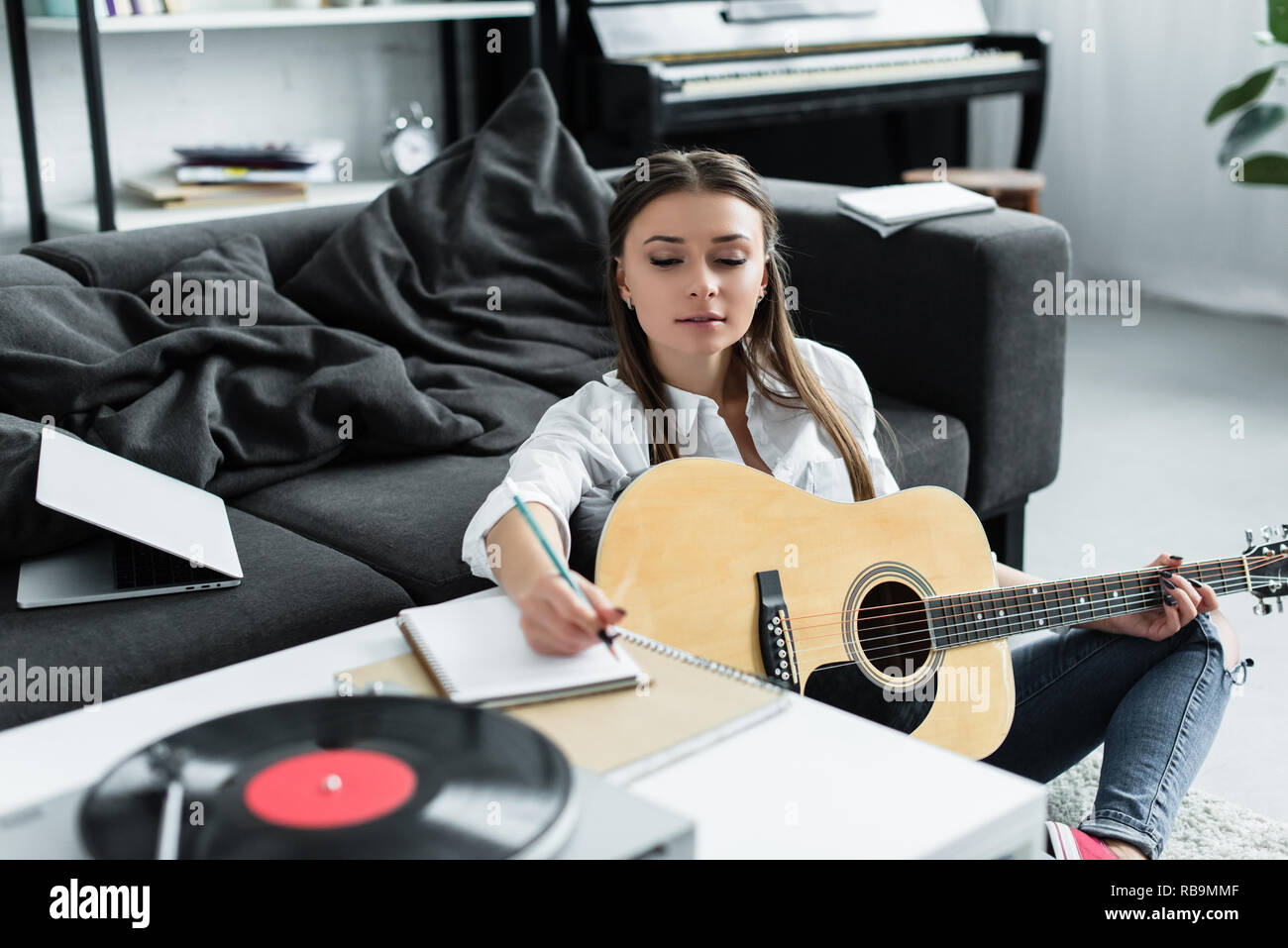Focus sélectif de fille avec guitare acoustique écrit dans l'ordinateur portable tout en composant la musique à la maison Banque D'Images