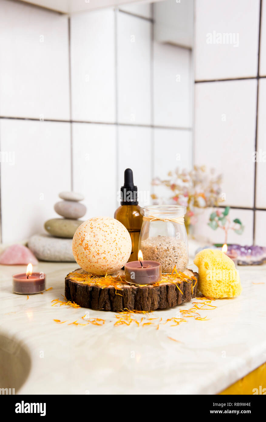 Vue latérale d'accueil produits wellness spa bath bomb orange, arôme, sel de bain, éponge de mer, plateau de bougies allumées. Ensemble très zen, arbre d'amour, de l'améthyste cristal. Banque D'Images