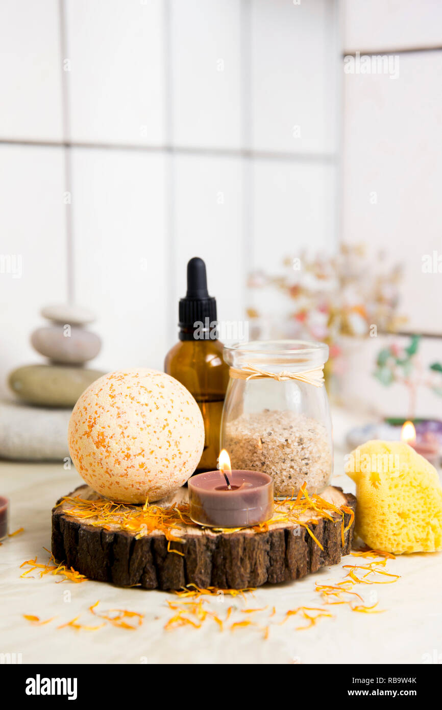 Vue latérale d'accueil produits wellness spa bath bomb orange, arôme, sel de bain, éponge de mer, plateau de bougies allumées. Ensemble très zen, arbre d'amour, de l'améthyste cristal. Banque D'Images