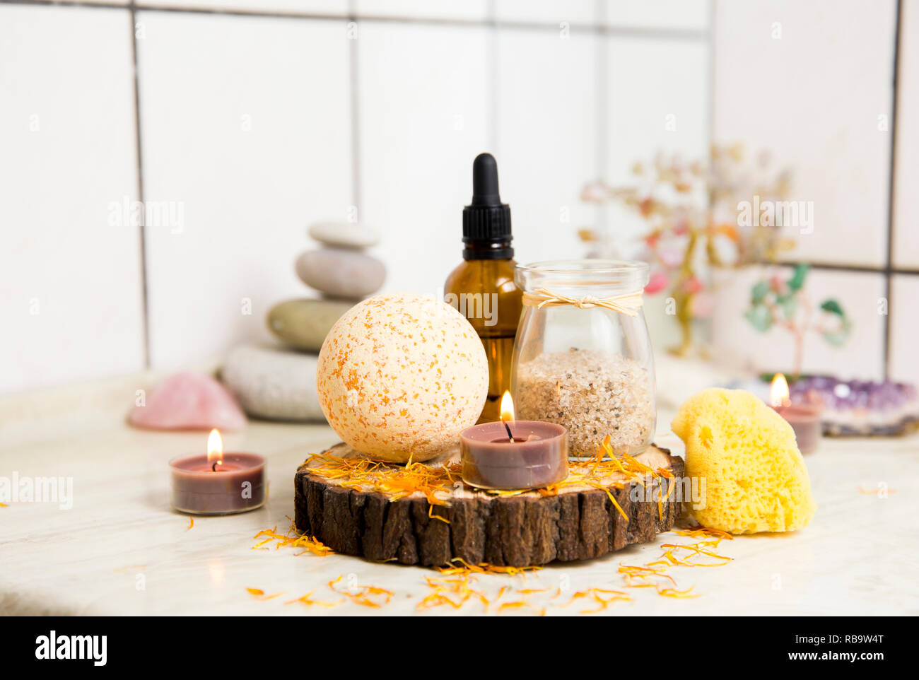 Vue latérale d'accueil produits wellness spa bath bomb orange, arôme, sel de bain, éponge de mer, plateau de bougies allumées. Ensemble très zen, arbre d'amour, de l'améthyste cristal. Banque D'Images