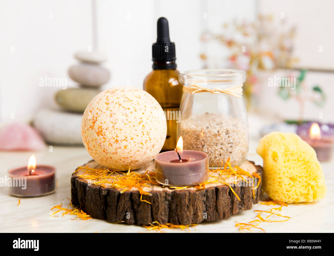 Vue latérale d'accueil produits wellness spa bath bomb orange, arôme, sel de bain, éponge de mer, plateau de bougies allumées. Ensemble très zen, arbre d'amour, de l'améthyste cristal. Banque D'Images