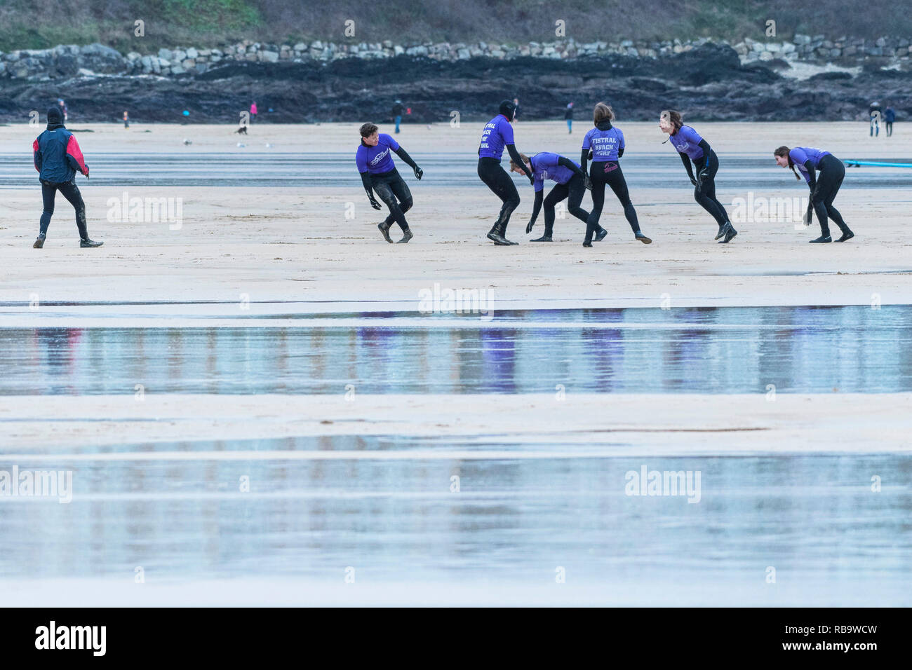 Les surfeurs débutants l'échauffement au début d'une leçon de surf à la plage de Fistral Newquay en Cornouailles. Banque D'Images