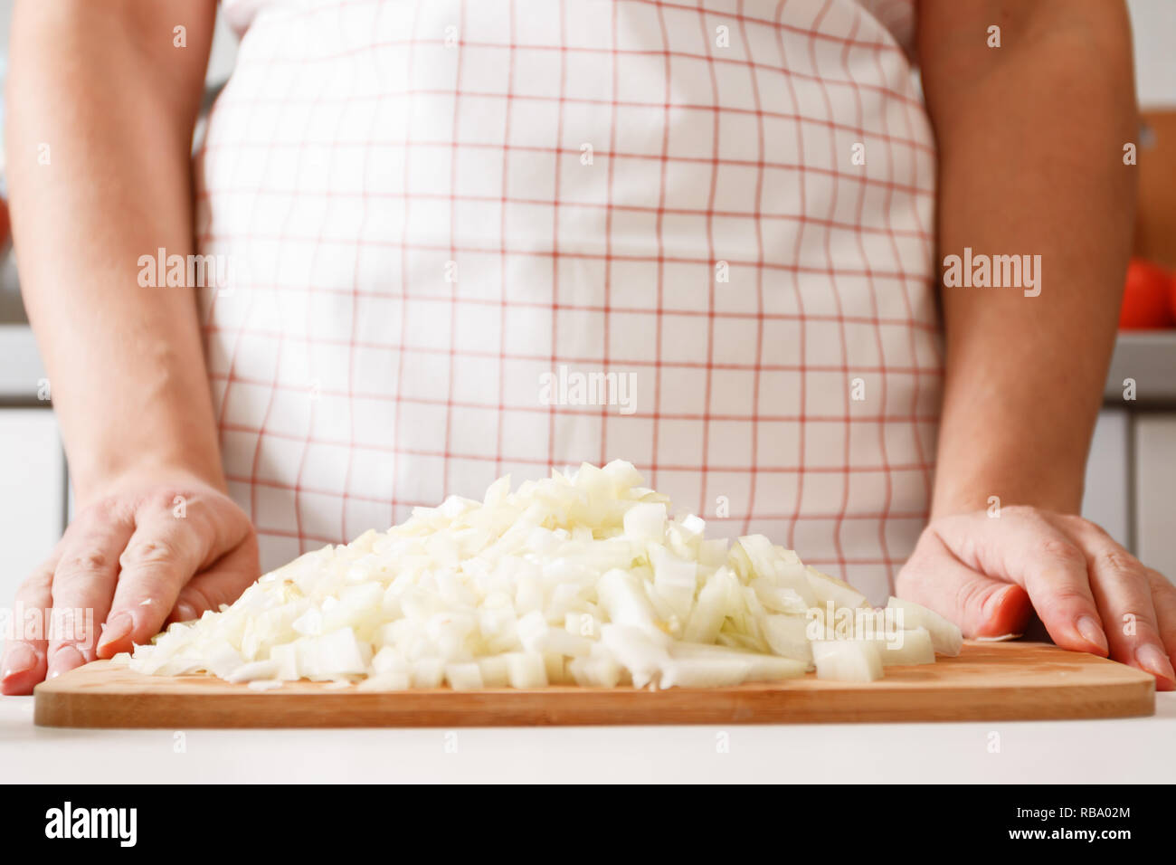 Une femme de cuisiniers dans la cuisine, sur une planche en bois se trouve une pile d'oignon haché. Les aliments frais et sain. Close-up Banque D'Images