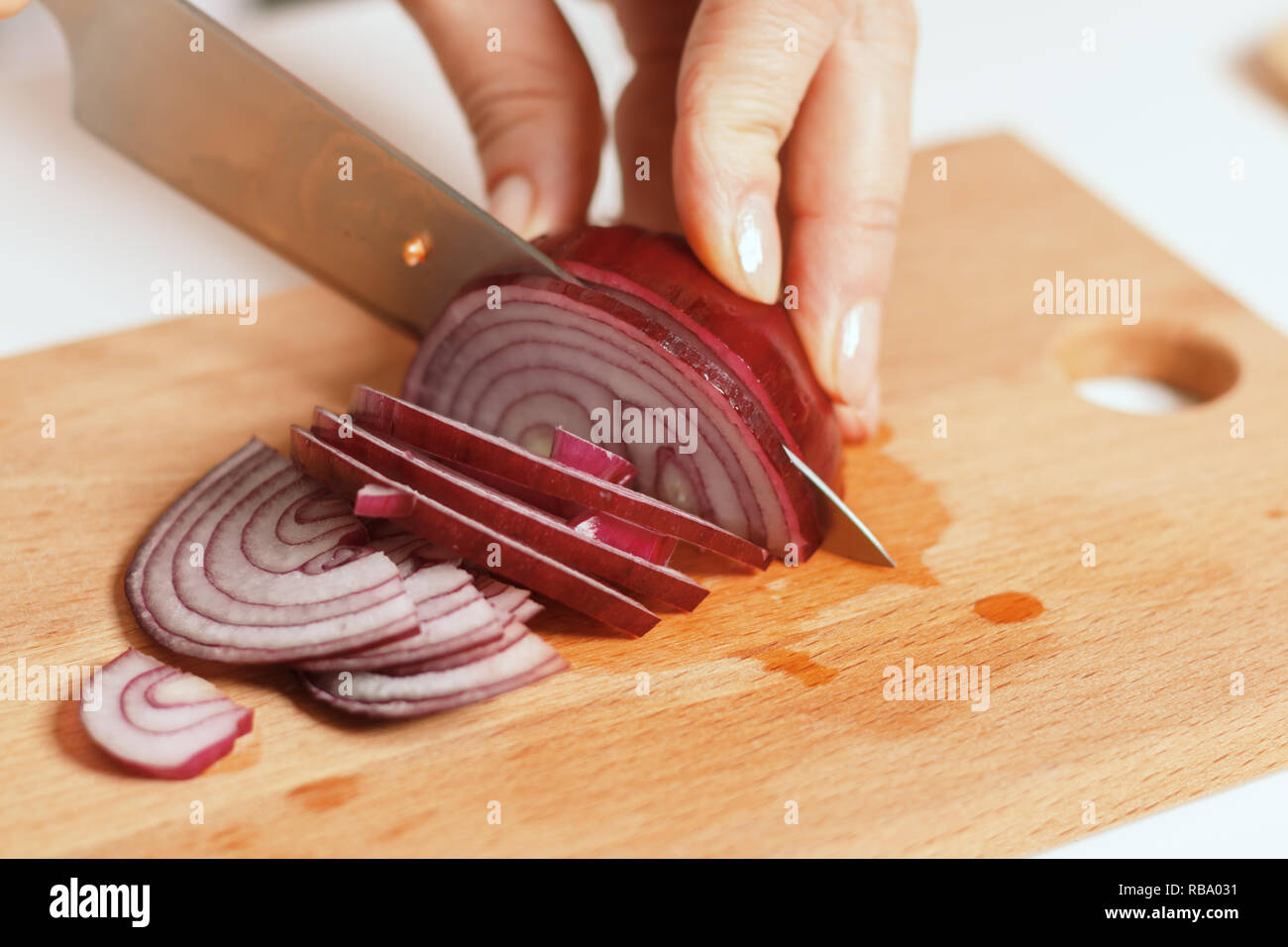 La cuisine du terroir. Femme dans la cuisine couper un oignon sur une planche de bois. Les aliments frais et sain.Close-up Banque D'Images