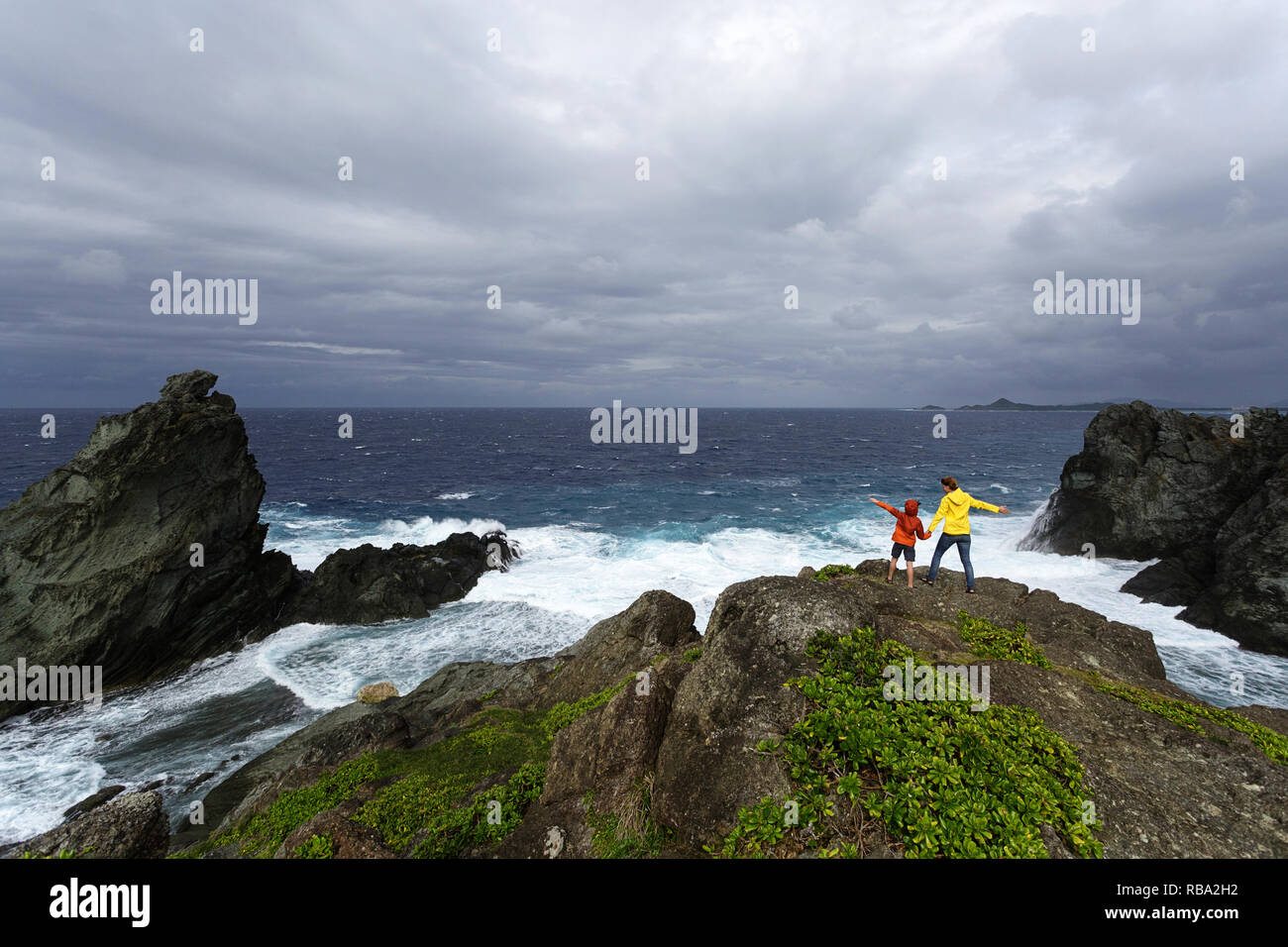 La mère et le fils à la recherche à l'état de la mer sur la côte sauvage à Uganzaki dans le phare de l'Île Ishigaki, Japon Okinawa Banque D'Images
