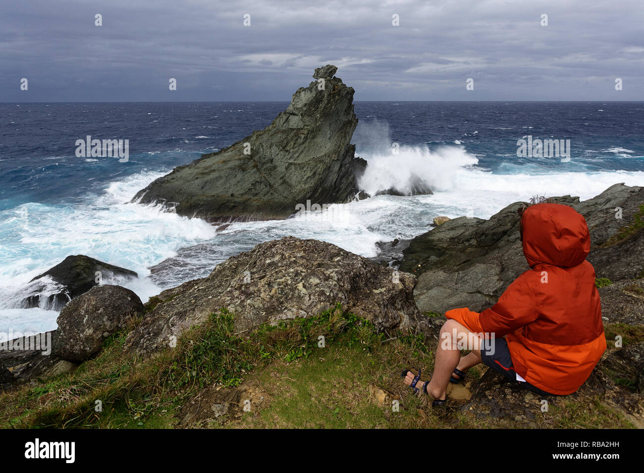 Jeune garçon à la recherche à l'état de la mer sur la côte sauvage à Uganzaki dans le phare de l'Île Ishigaki, Japon Okinawa Banque D'Images
