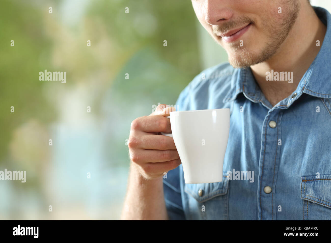 Close up portrait of a man holding détendue une boisson chaude tasse à la maison Banque D'Images
