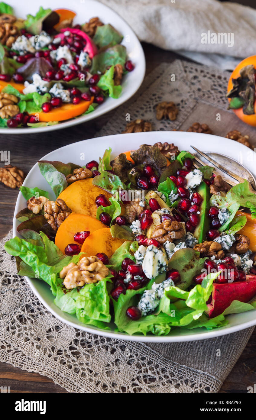 Salade d'automne avec kaki, grenade, fromage bleu et noix sur fond de bois rustique. Focus sélectif. Banque D'Images