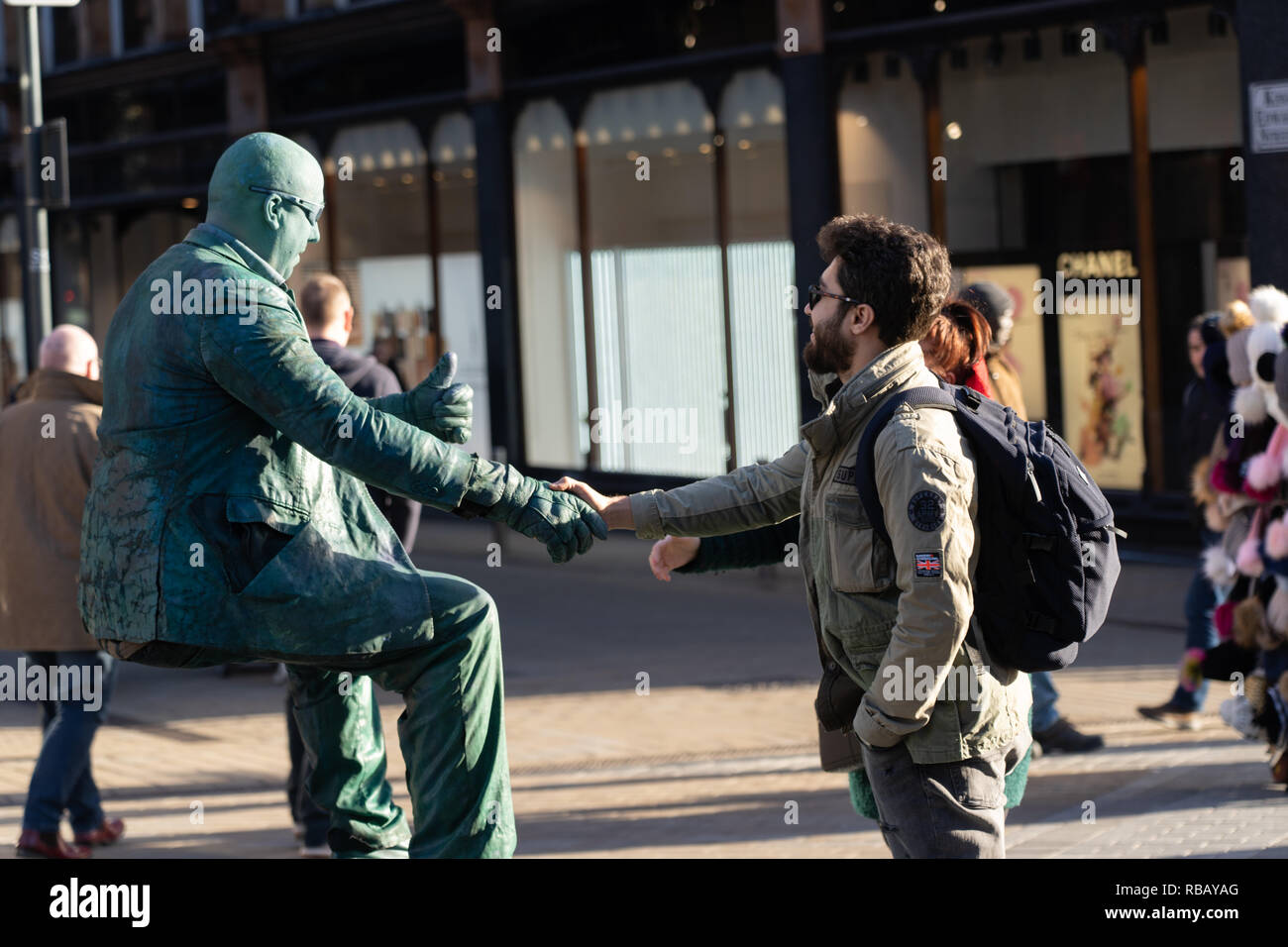Un homme de lévitation qui se met à la main avec un client dans la rue, Briggate, Leeds, West Yorkshire, Angleterre, ROYAUME-UNI. Banque D'Images