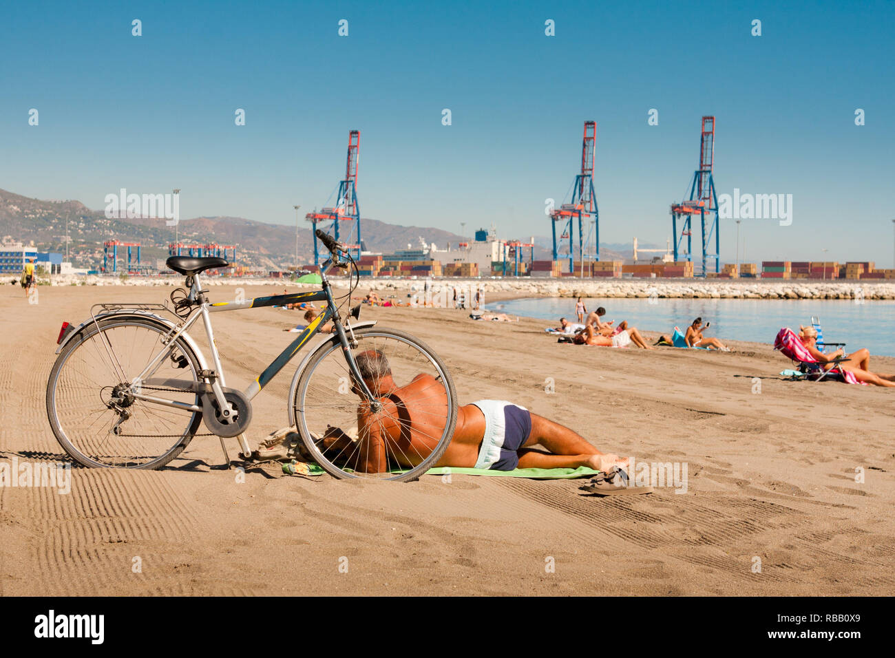 Un homme à vélo sur la plage de la ville de Malaga - Espagne Banque D'Images