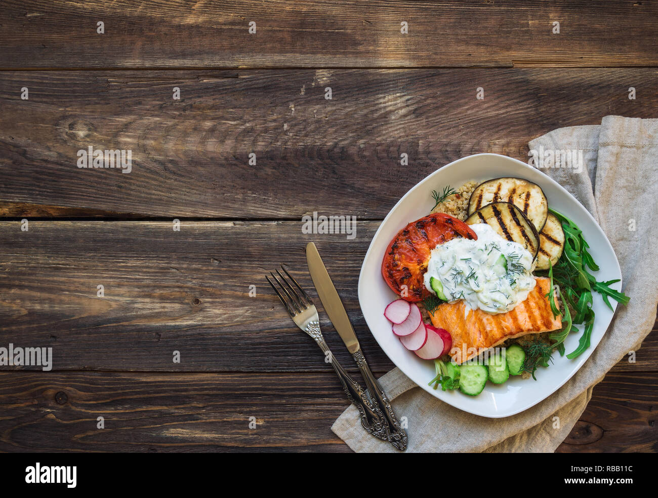 Saumon grillé, tomates et aubergines avec le quinoa et sauce tzatziki sur fond de bois rustique. Dîner sain. Vue d'en haut. Copie espace salon. Banque D'Images