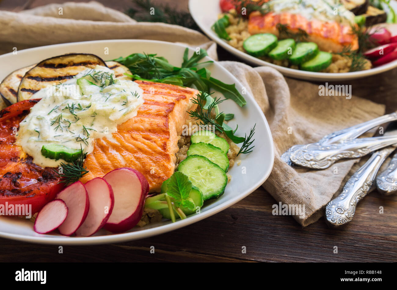 Saumon grillé, tomates et aubergines avec le quinoa et sauce tzatziki sur fond de bois rustique. Dîner sain. Focus sélectif. Banque D'Images