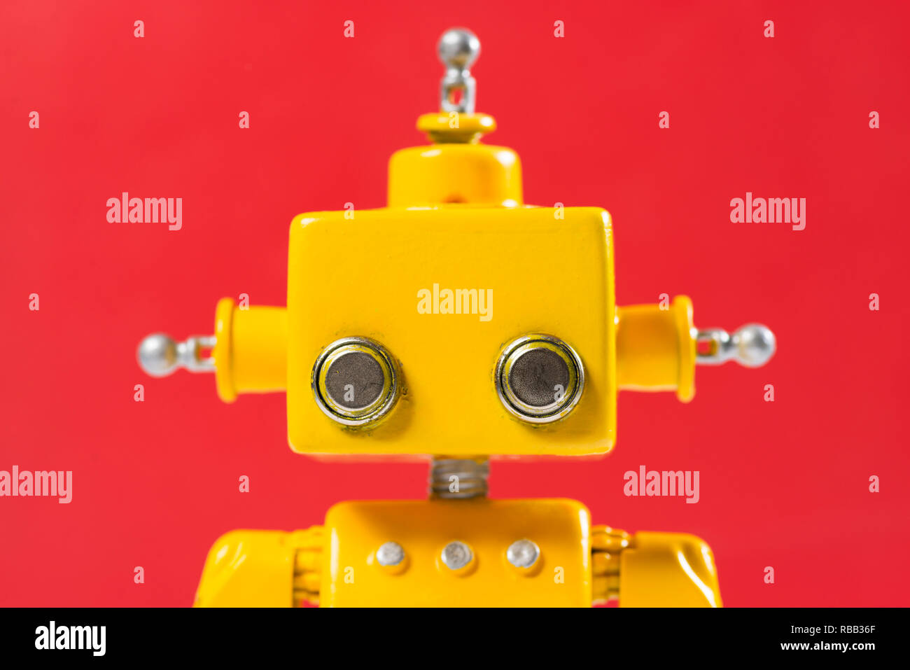 Portrait of a Cute, jaune, fait main robot sur un fond rouge. Banque D'Images