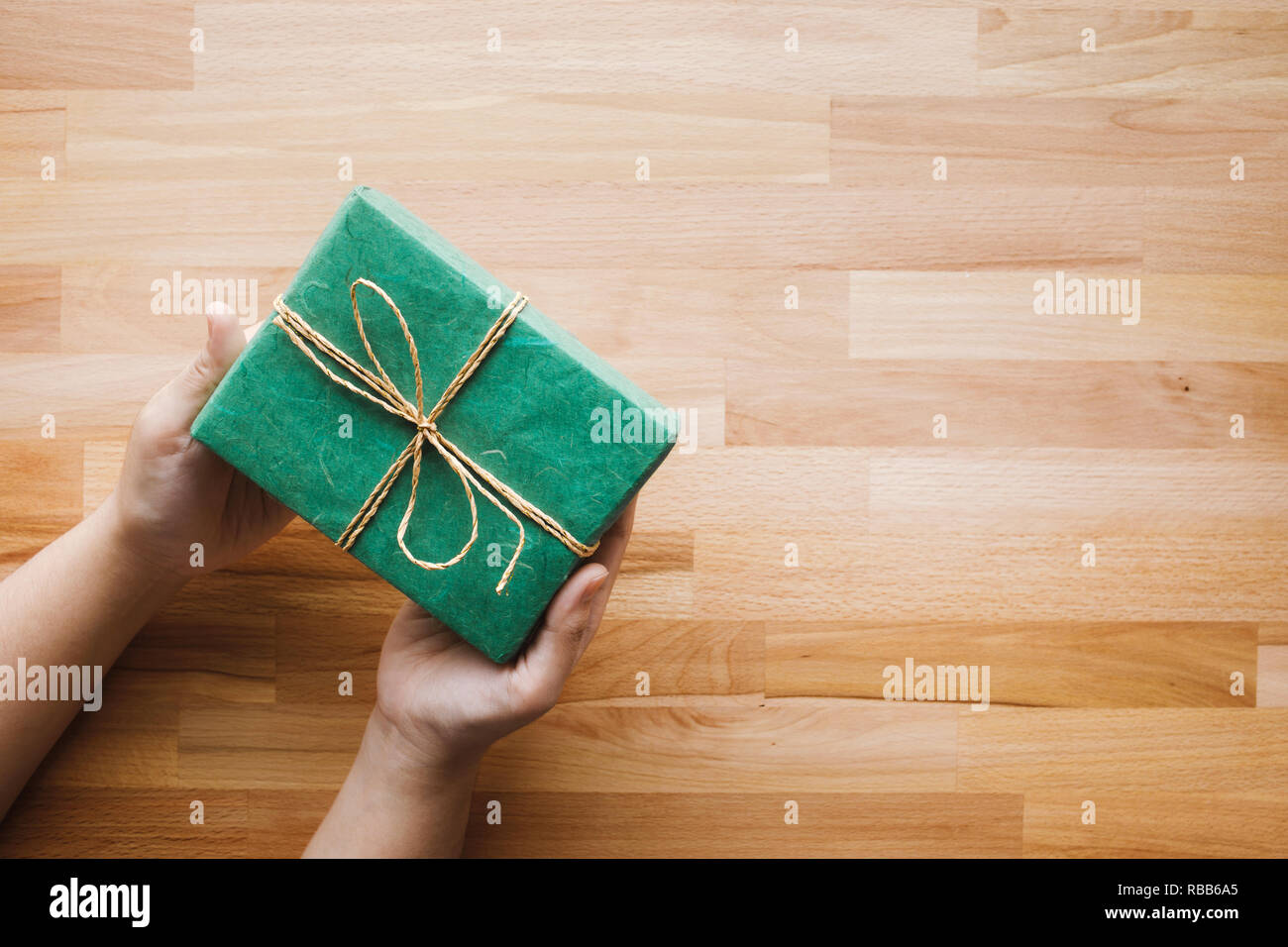 Boîte cadeau vert sur fille main en bois avec copie espace background.Noël Nouvel an et anniversaire idées concepts Banque D'Images