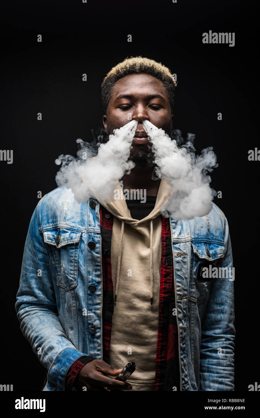 Jeune homme africain vape fume isol sur fond sombre Photo Stock - Alamy