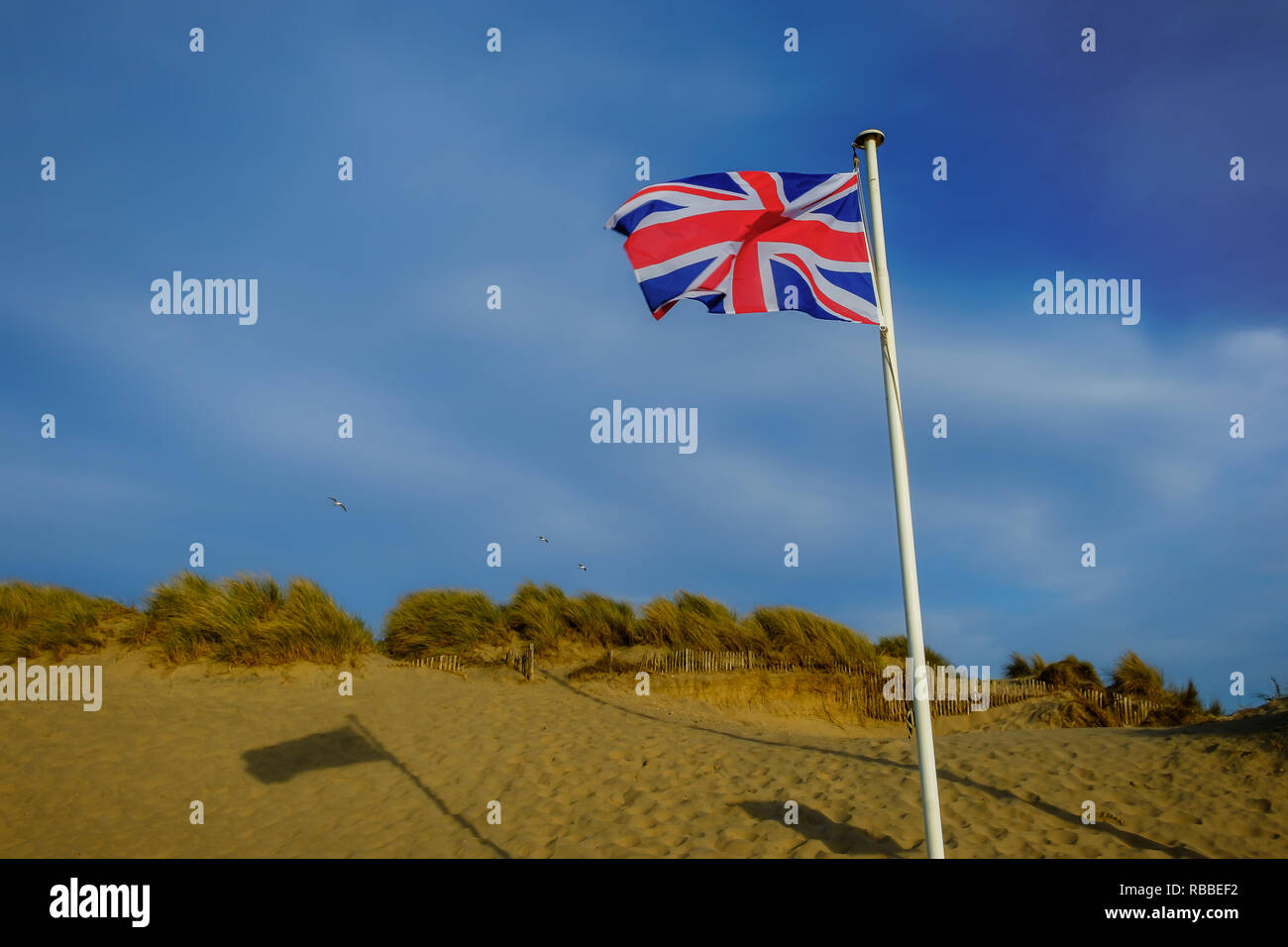 Drapeau britannique devant une dune de Camber Sands Beach, East Sussex, Royaume-Uni Banque D'Images
