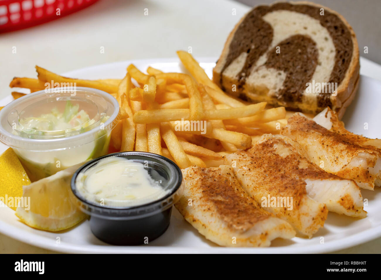 Bar nourriture : poisson cuit au four avec plaque en marbre, frites, pain de seigle, frites, salade de chou, de quartiers de citron et sauce tartare. Banque D'Images