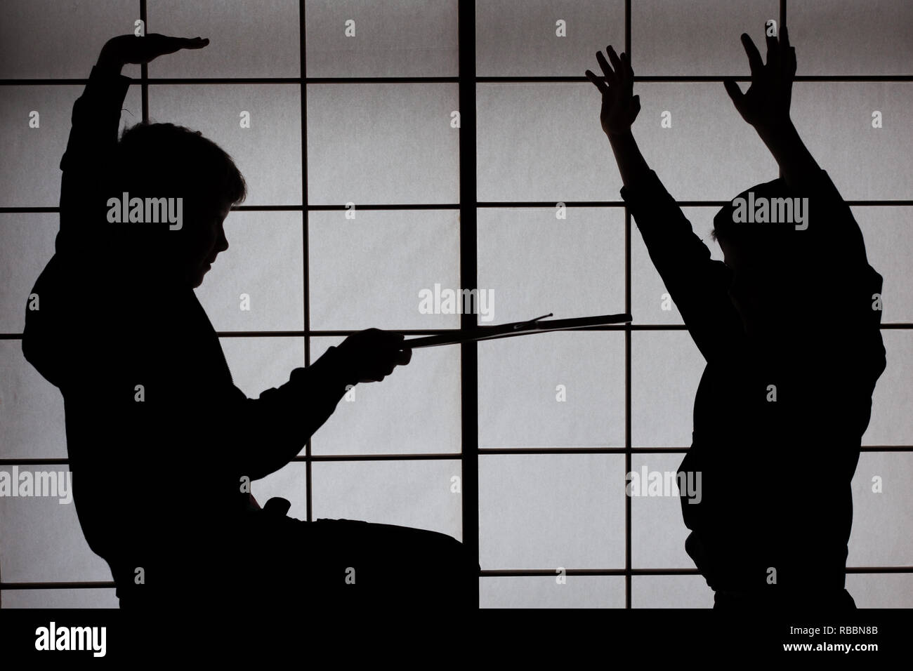 Garçons Lutte contre un écran shoji en silhouette Banque D'Images