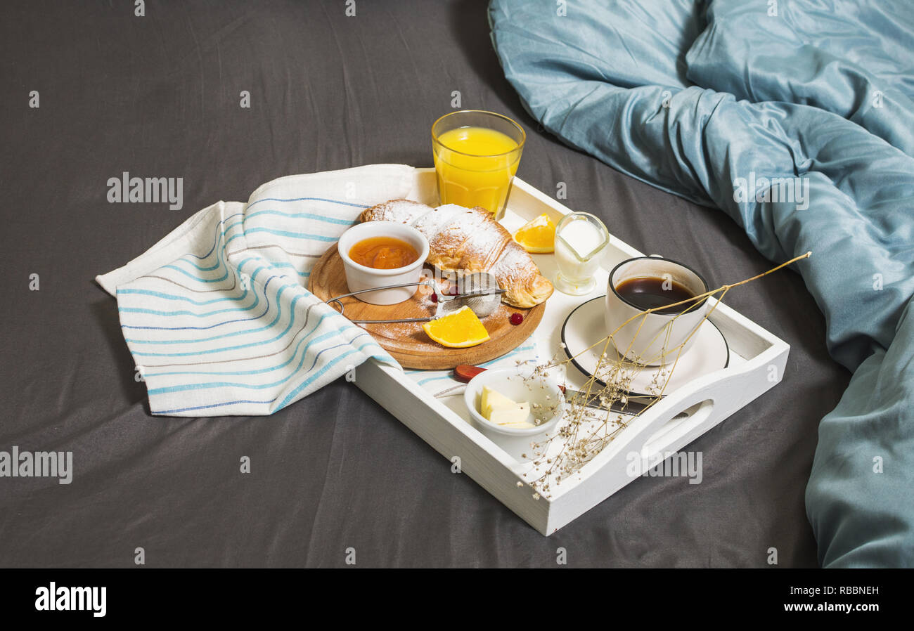 Petit-déjeuner au lit avec café, croissants et jus d'orange sur fond blanc. Banque D'Images