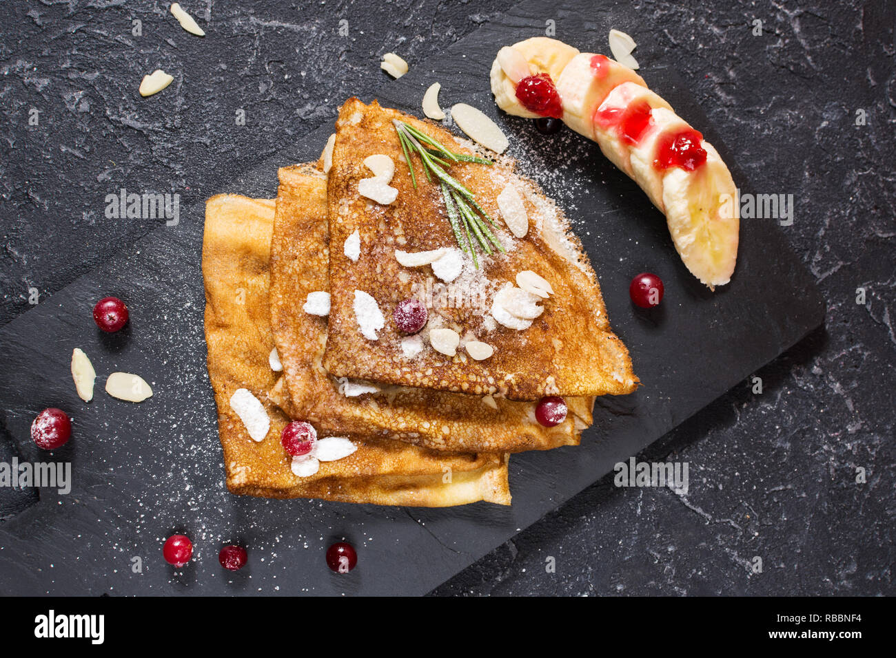 Crêpes traditionnelles de banane et fruits rouges sur fond noir en noir Banque D'Images