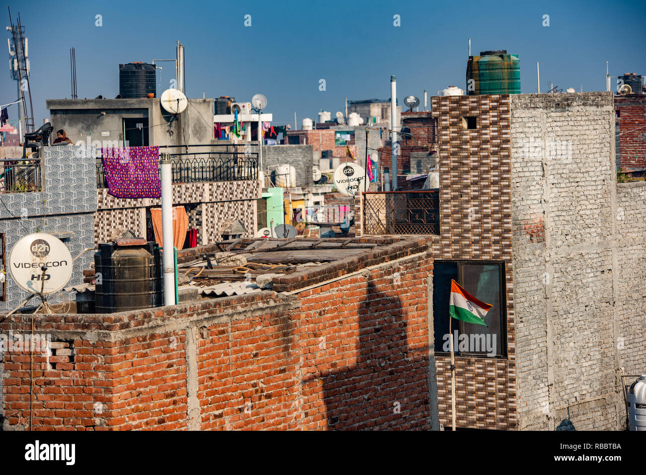 Une scène sur le toit ensoleillée à JJ Colonie Madanpur Khadar, New Delhi faire un paysage de satellites et les réservoirs d'eau avec des plats de séchage des vêtements. Banque D'Images